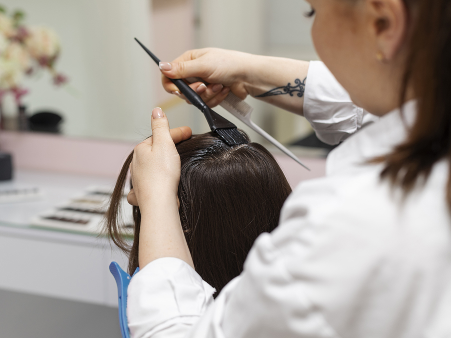 A client's long hair being smoothed through after a colour