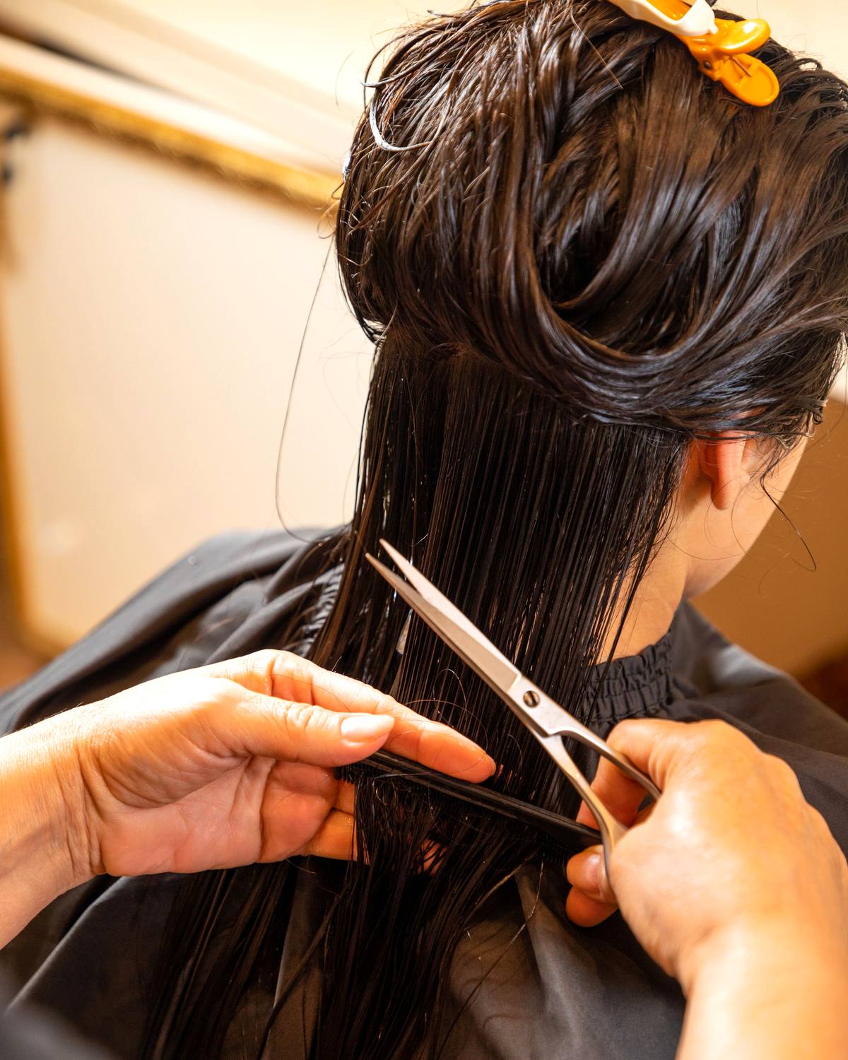 A stylist working through a client's long hair at the chair