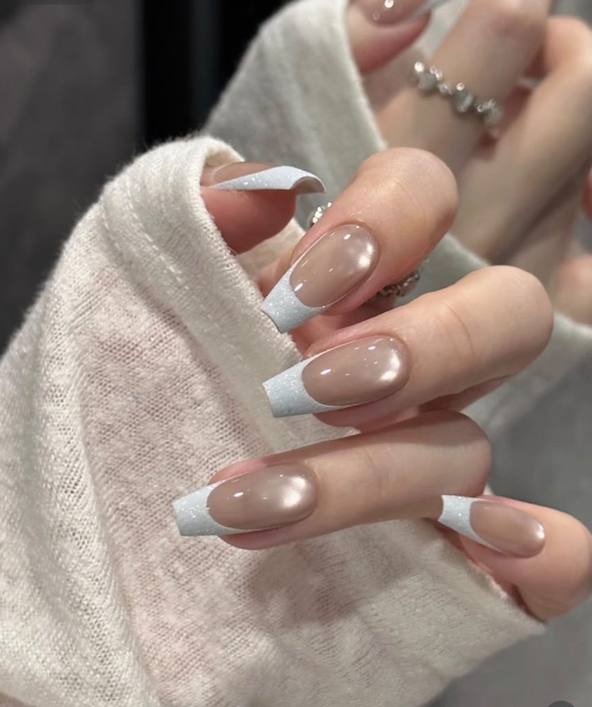 Glossy nude nails with a shimmering white French tip